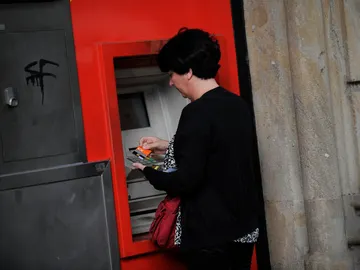 Una mujer saca dinero de un cajero automático Una mujer saca dinero de un cajero automático
