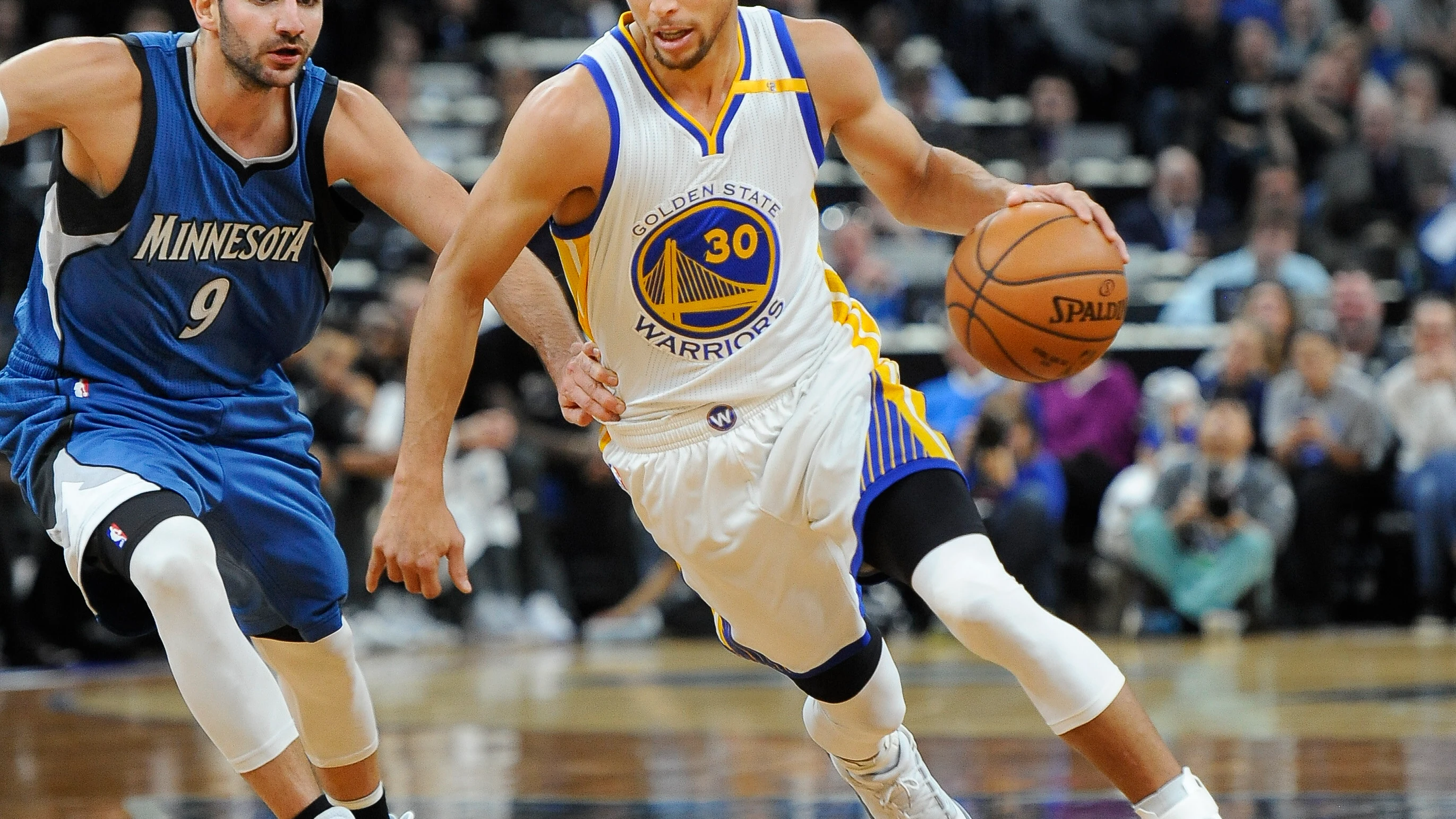 Stephen Curry corre con el balón mientras es defendido por Ricky Rubio