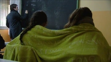 Imagen de dos alumnas dando clase abrigadas con una manta para soportar el frío