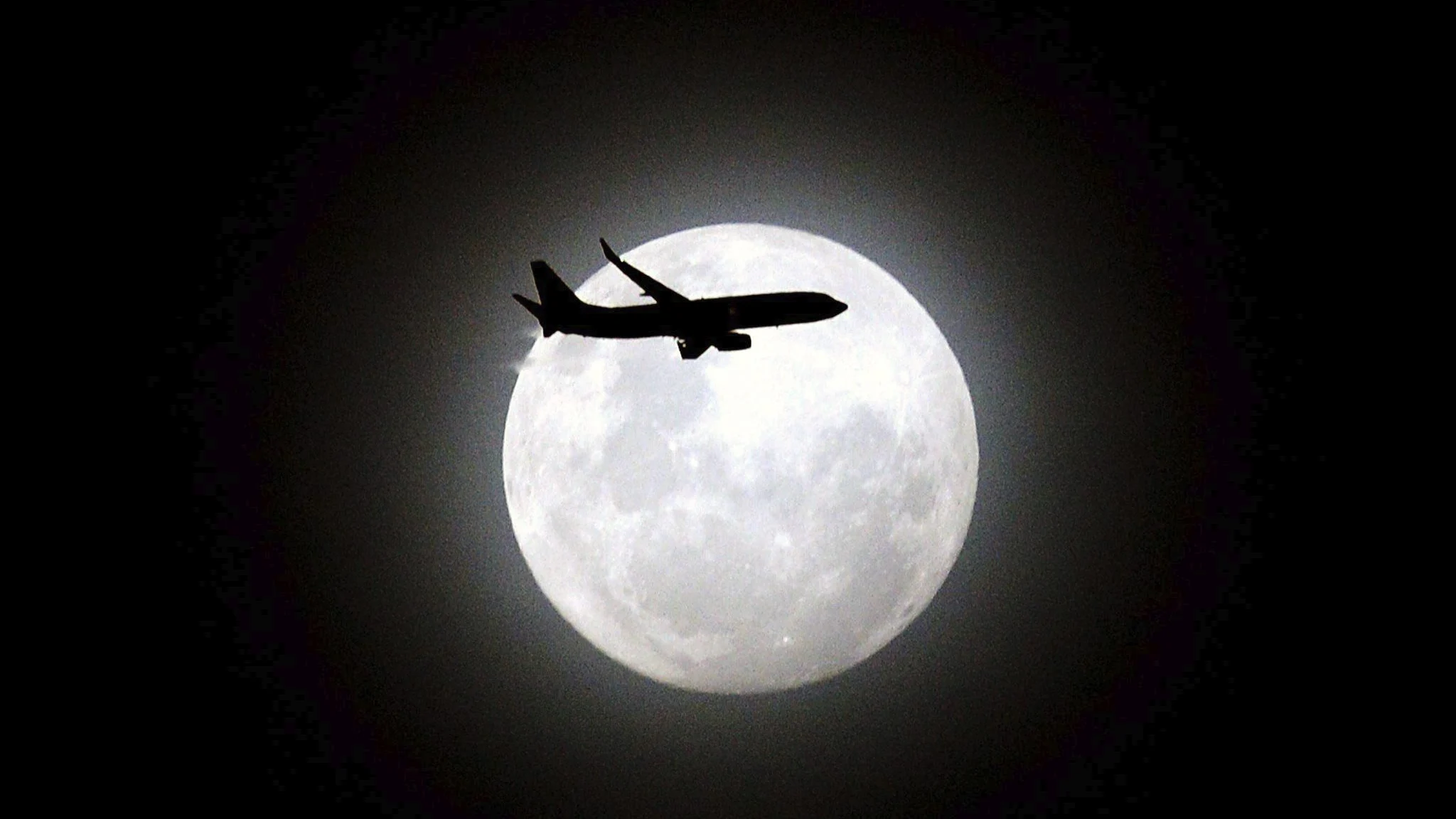 Un avión de pasajeros pasa delante de la tercera y última luna en perigeo sobre la playa de Maroubra en Sídney (Australia)