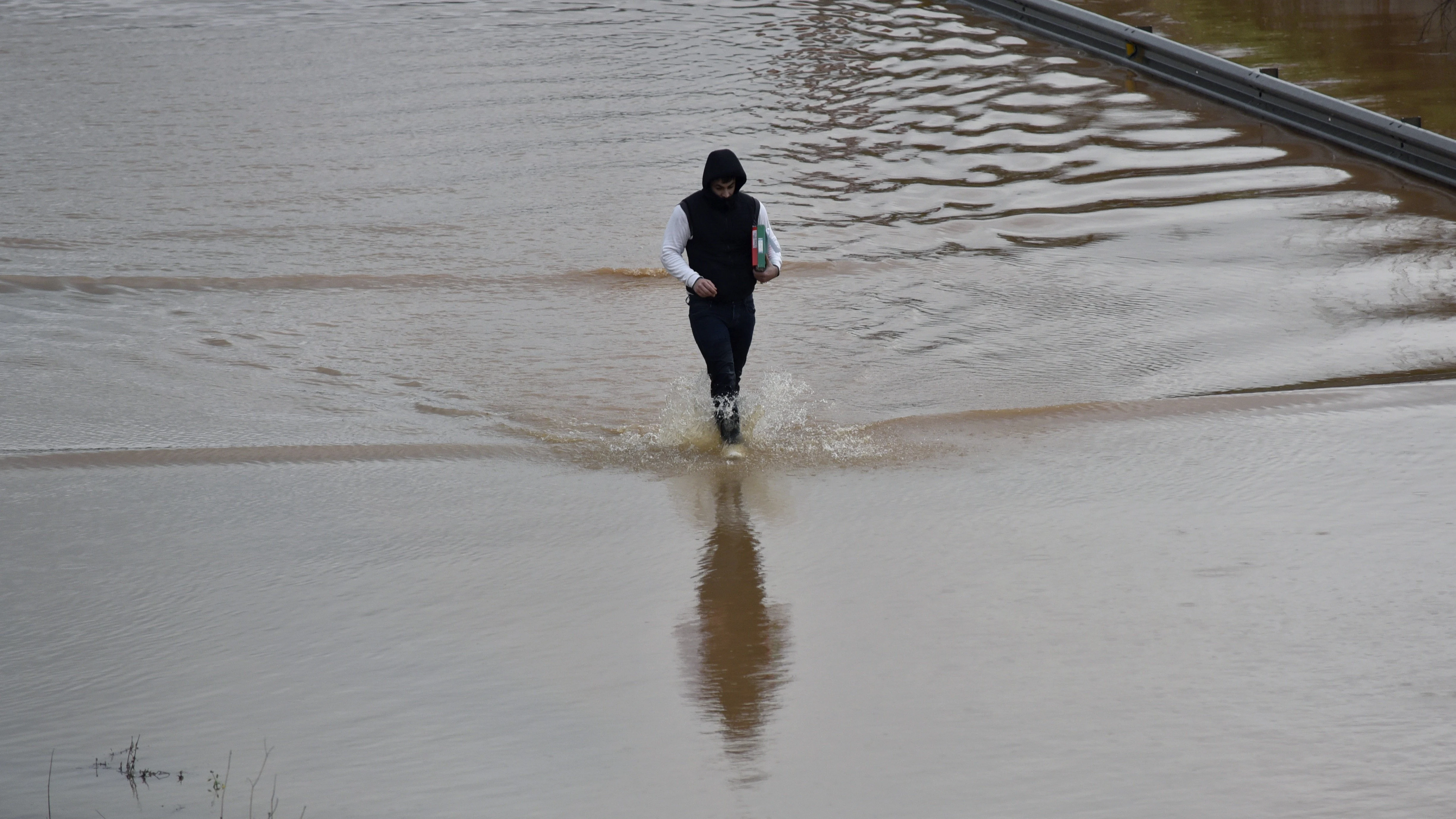 Un vecino cruza una carretera inundada del municipio de Campos (Mallorca).