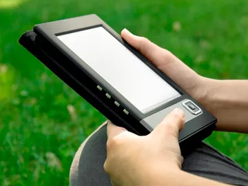 Un joven lee un libro electrónico en su e-reader Un joven lee un libro electrónico en su e-reader