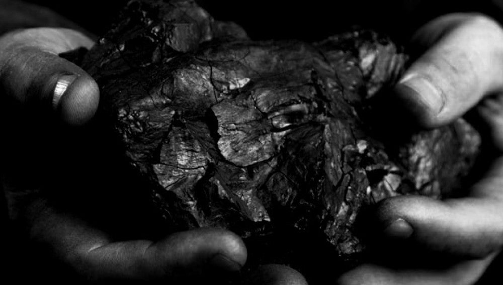 Unas manos cogiendo carbón 