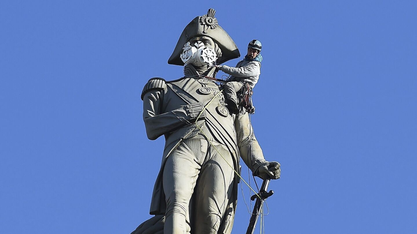 Un activista de Greenpeace coloca una m&aacute;scara a la estatua de Nelson en la plaza de Trafalgar en Londres durante una protesta contra la poluci&oacute;n