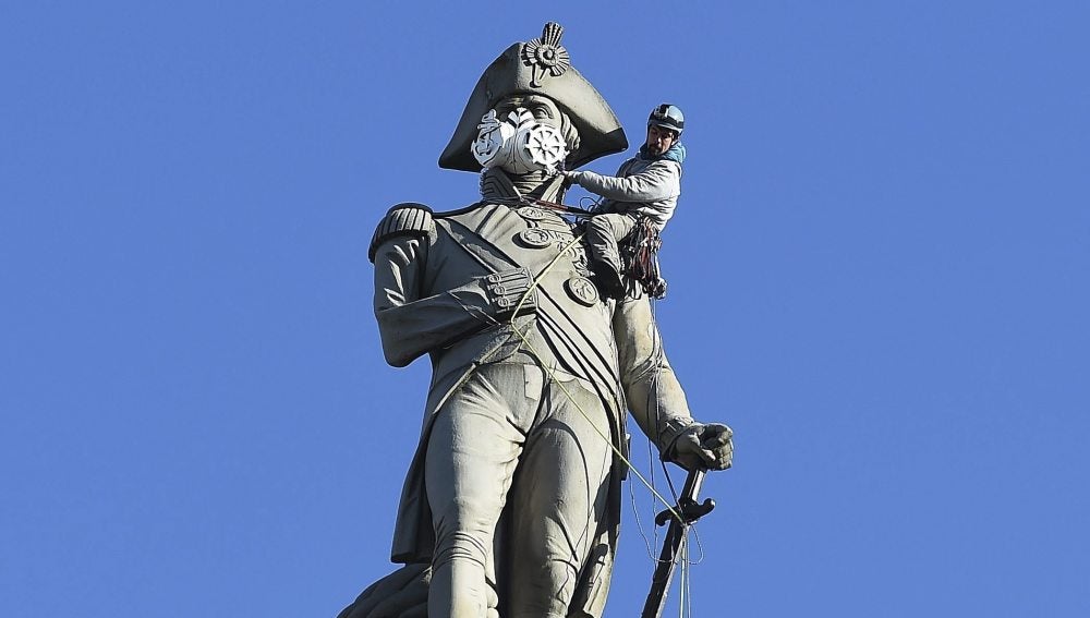 Un activista de Greenpeace coloca una máscara a la estatua de Nelson en la plaza de Trafalgar en Londres durante una protesta contra la polución
