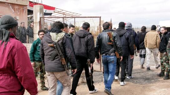 Hombres sirios armados durante el proceso de registro de sus nombres y entrega de armas, en Damasco