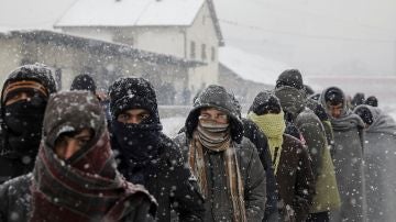 Migrantes esperan en fila para recibir comida fuera de un almacén abandonado en Belgrado