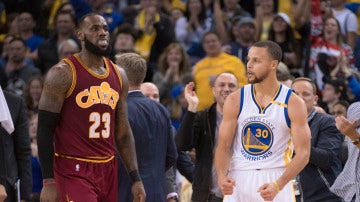 Stephen Curry celebra una canasta ante la mirada de LeBron James