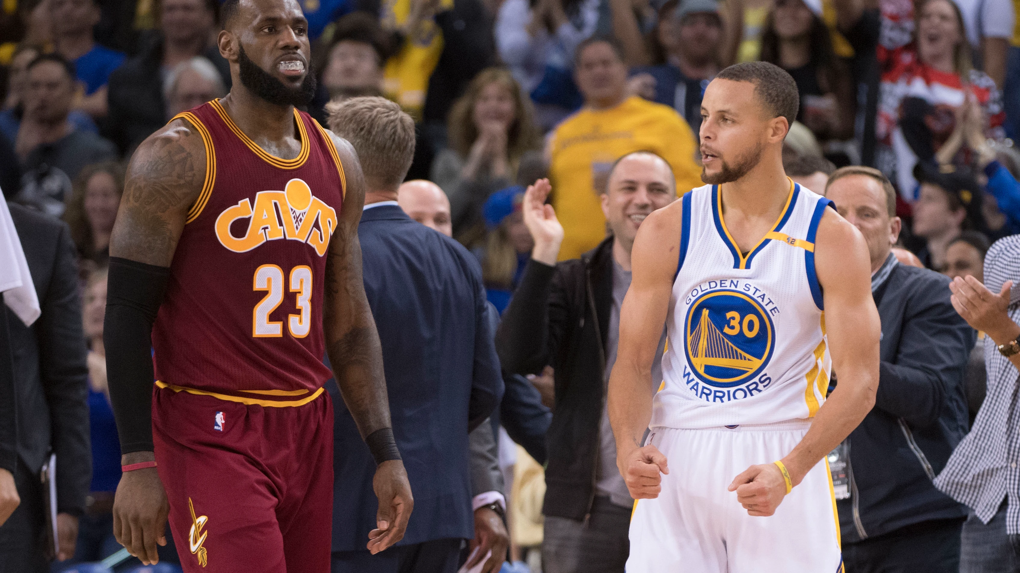 Stephen Curry celebra una canasta ante la mirada de LeBron James