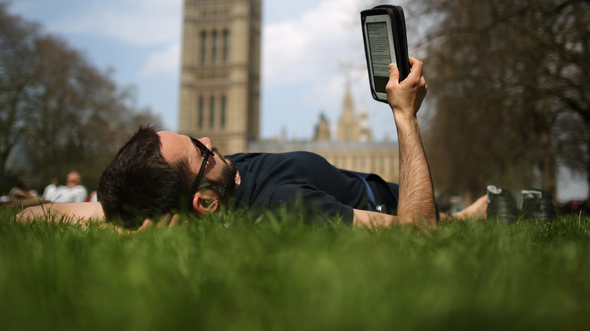 Un lector tumbado leyendo un libro electrónico