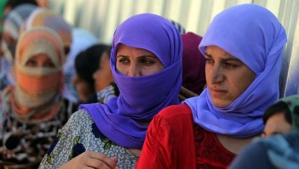 Varias mujeres hacen cola para coger comida en un campo de refugiados de Kurdistán