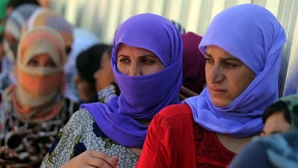 Varias mujeres hacen cola para coger comida en un campo de refugiados de Kurdistán