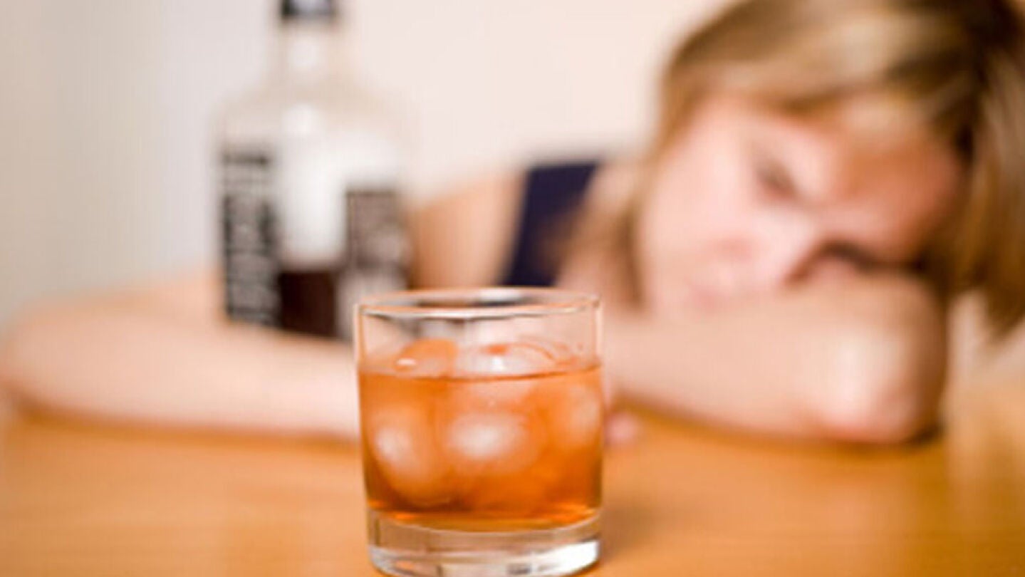Una mujer ante un vaso con alcohol