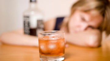 Una mujer ante un vaso con alcohol