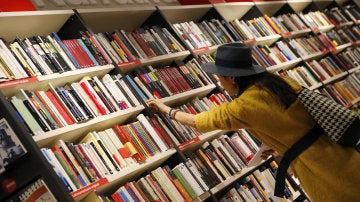 Una mujer mira libros en los estanterías de una librería