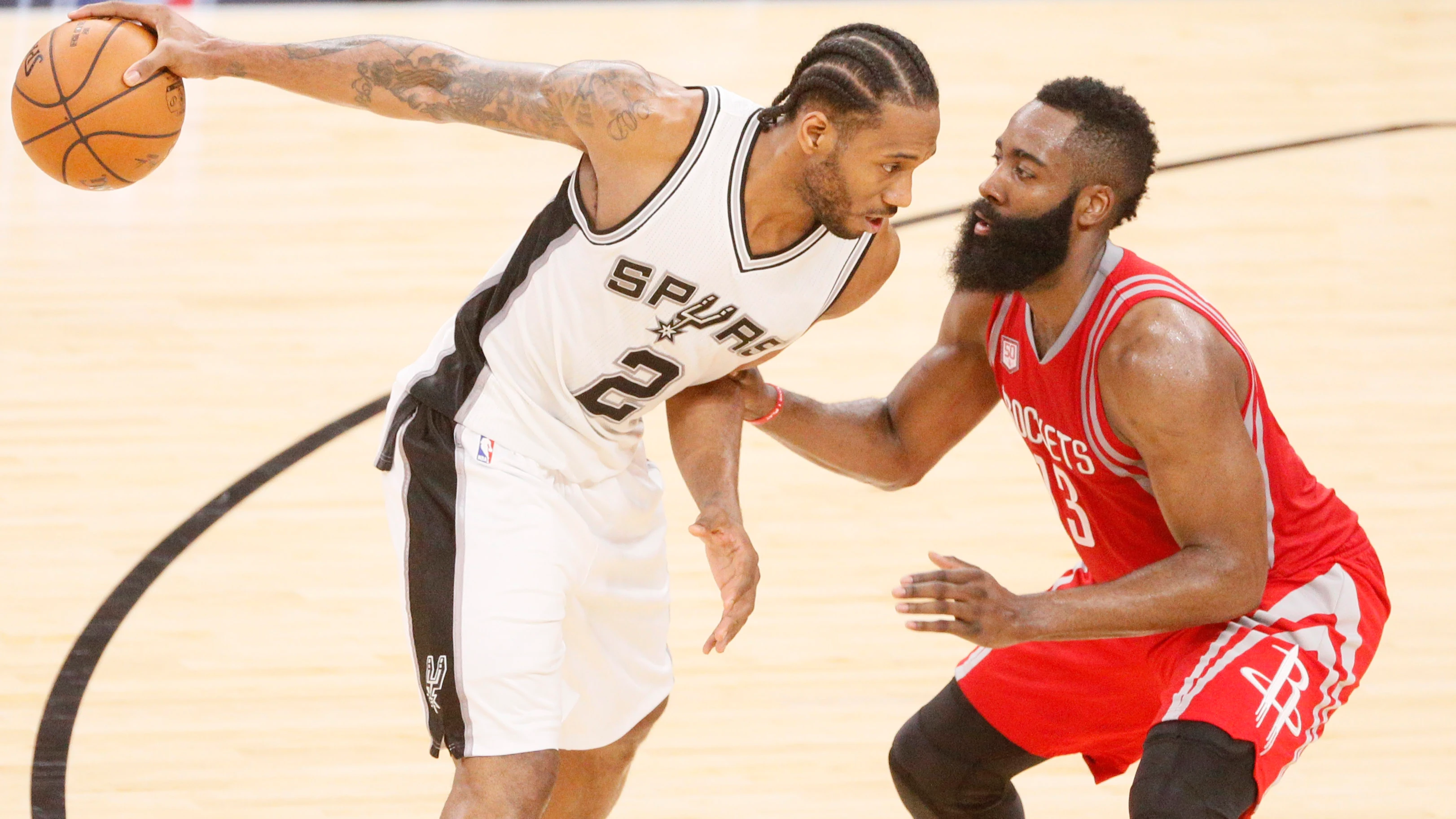 Kawhi Leonard sostiene el balón con una mano ante la defensa de James Harden