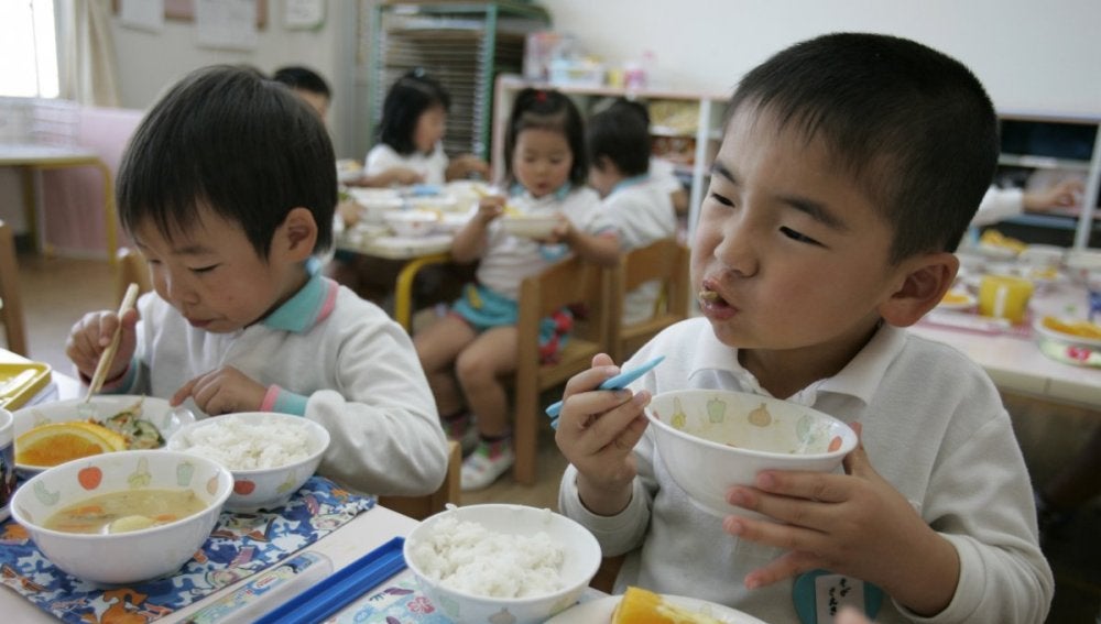 Dos niños disfrutan de su almuerzo en el comedor escolar