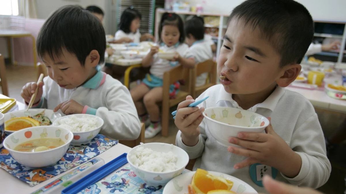 Dos niños disfrutan de su almuerzo en el comedor escolar