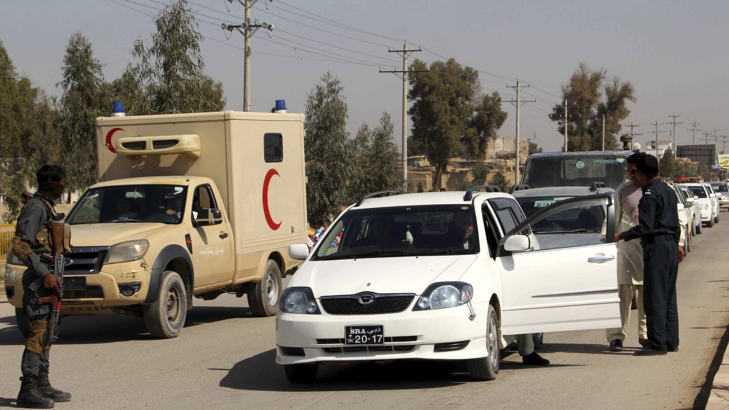 Oficiales de seguridad afgano registran a varios ciudadanos en un puesto de control en Helmand, Afganist&aacute;n