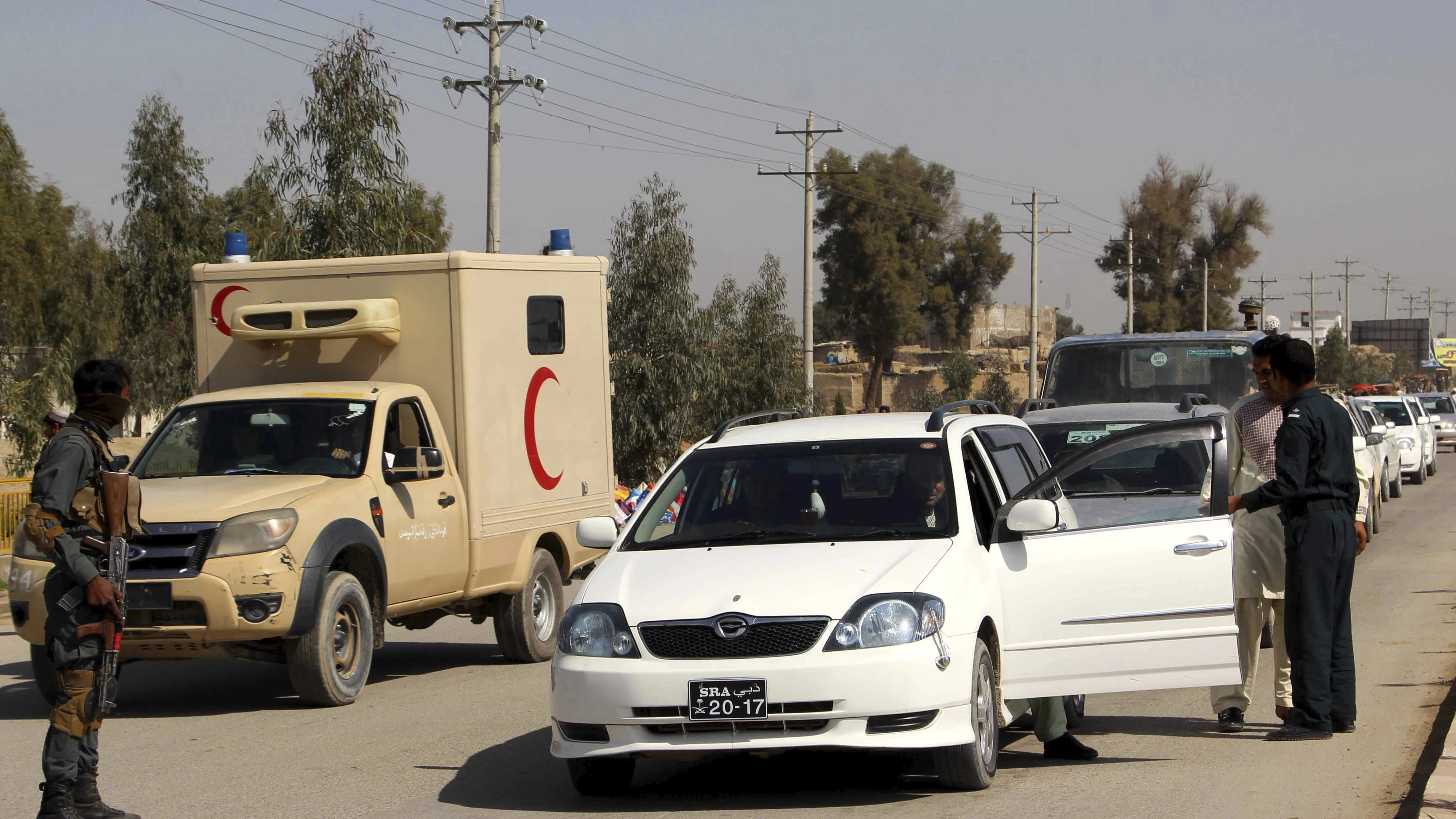 Oficiales de seguridad afgano registran a varios ciudadanos en un puesto de control en Helmand, Afganistán