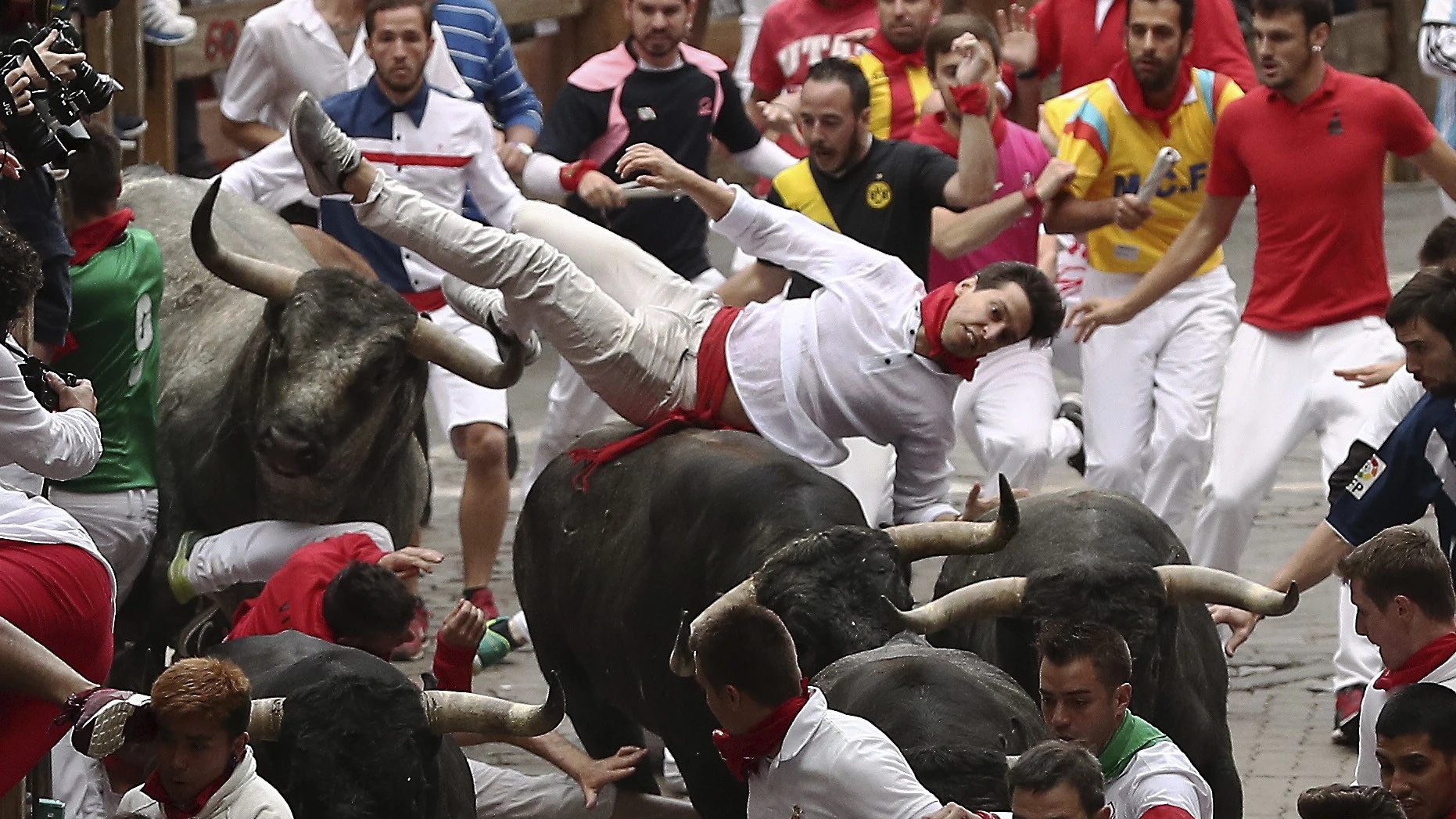 Los toros de Miura voltean a un mozo en el tramo final del recorrido por las calles de Pamplona.