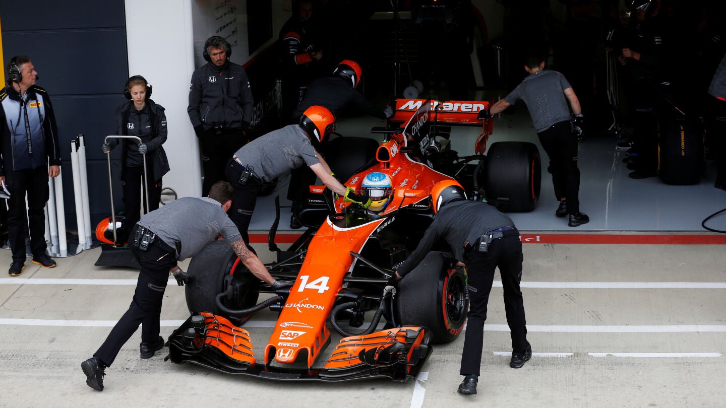 Fernando Alonso mete su coche en el box con la ayuda de sus mec&aacute;nicos
