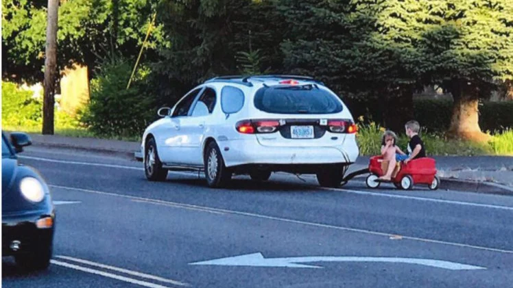 La mujer arrastrando a los niños con su coche