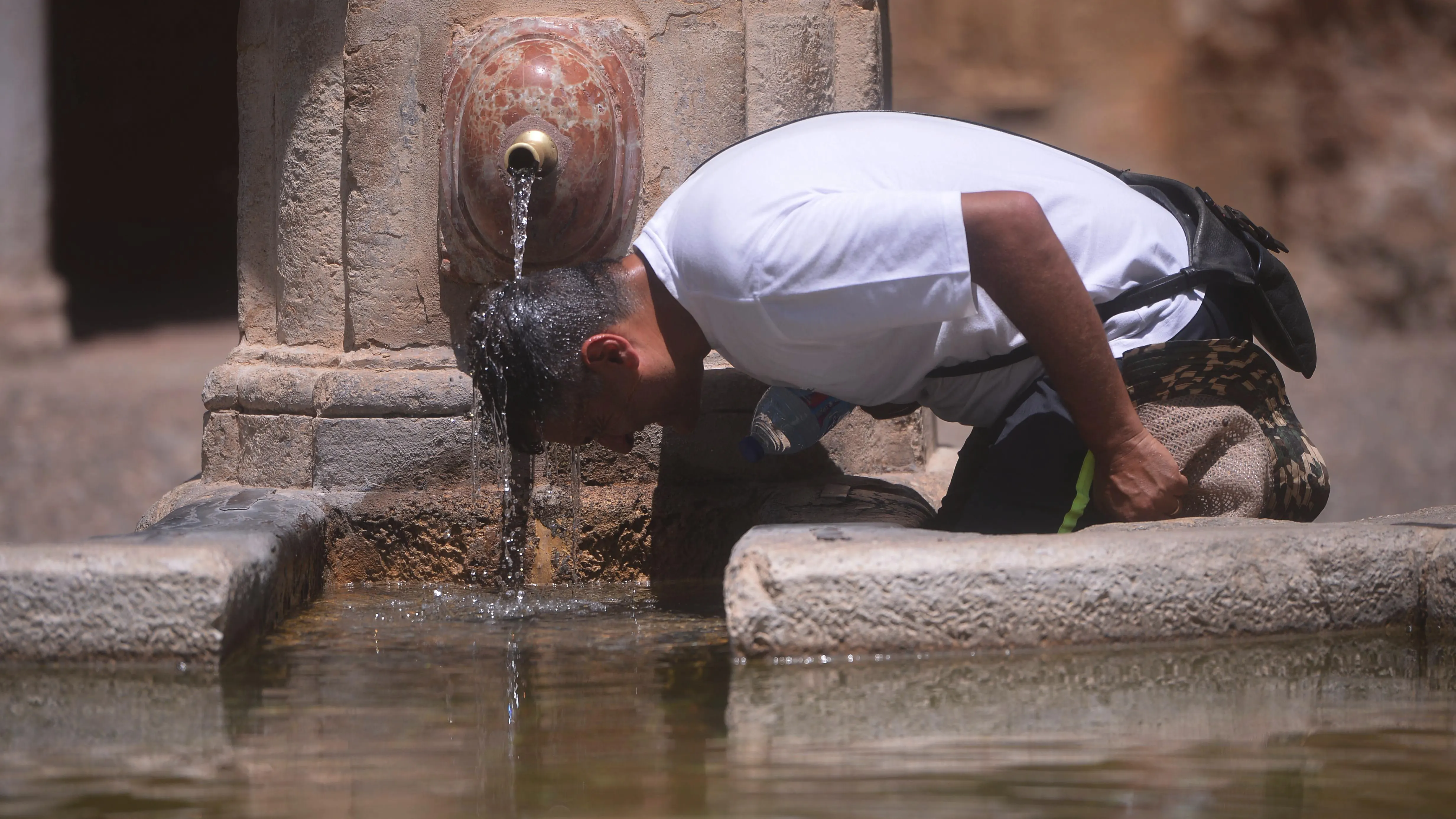 Un hombre combate el calor en una fuente