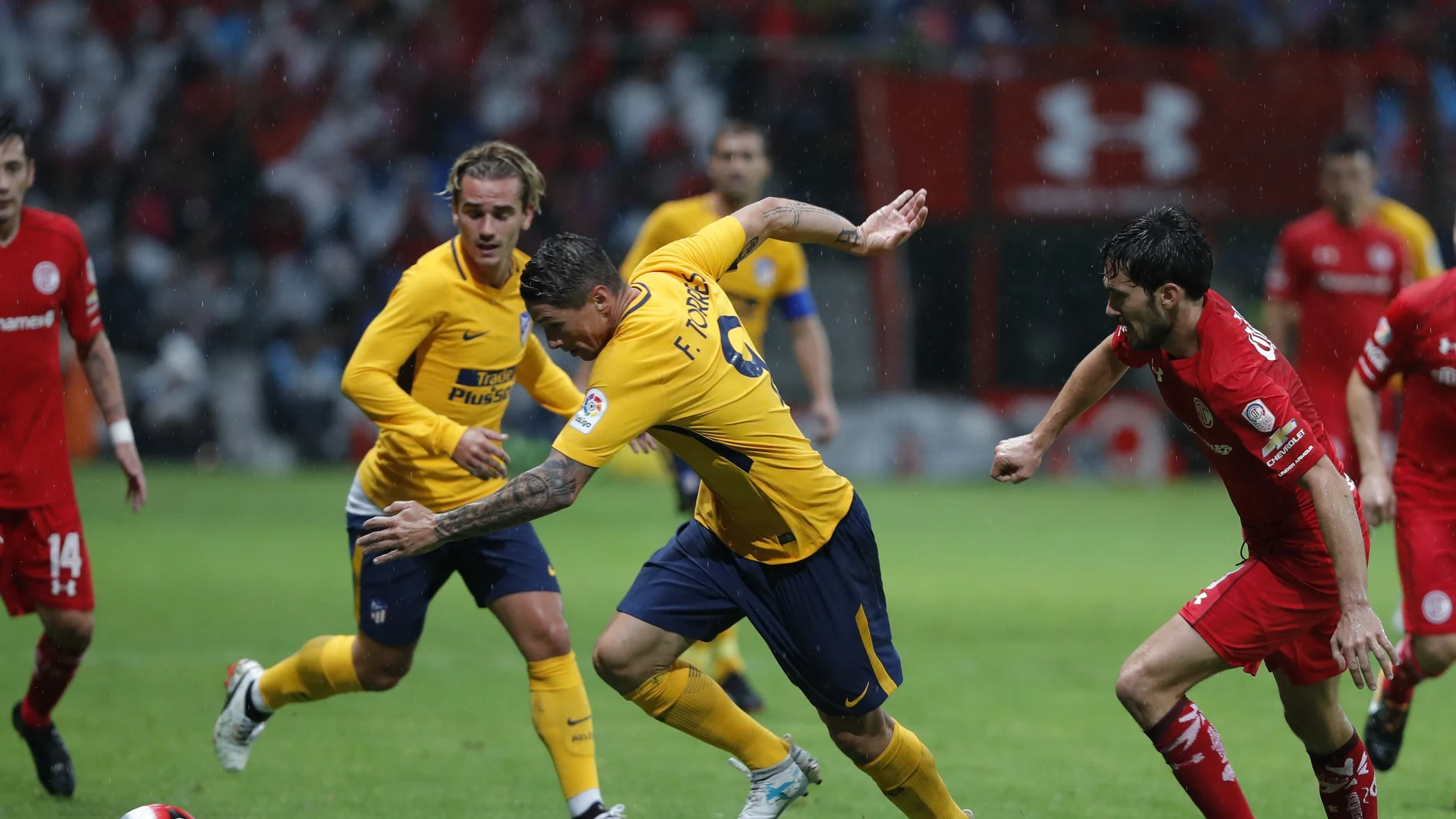 Fernando Torres intenta avanzar con el balón ante la mirada de Griezmann