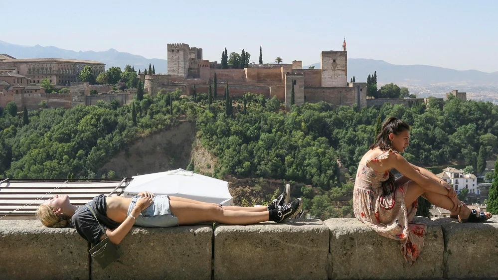 Unos turistas descansan y toman el sol en Granada.