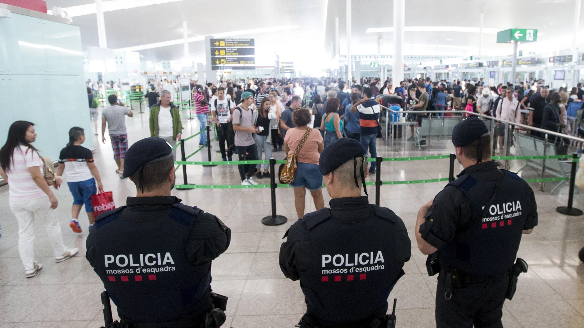 Agentes de los Mossos d'Esquadra controlan de los accesos a las puertas de embarque en el Aeropuerto de El Prat