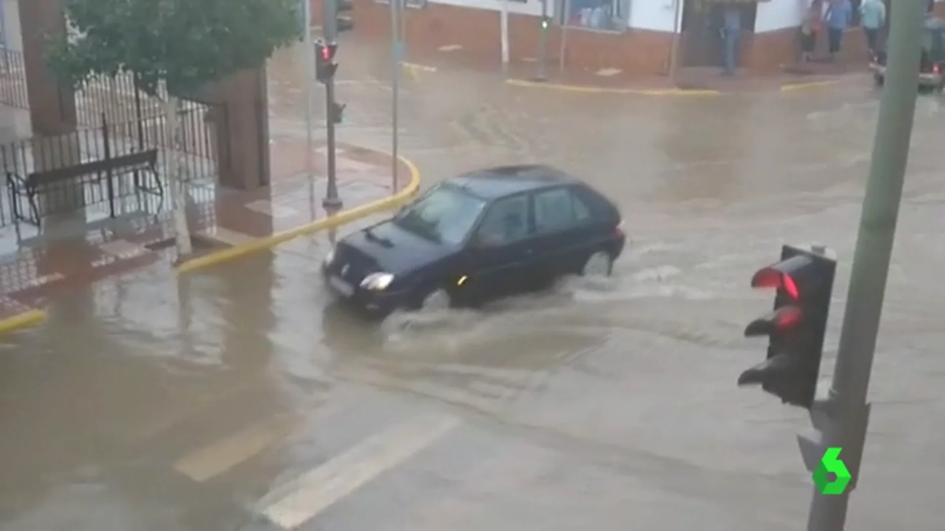 Un coche atravesando una calle de humilladero tras la tormenta