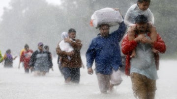 Los residentes caminan por zonas inundadas que deja la tormenta tropical Harvey en Beaumont Place, Houston