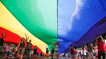 Varias personas portan una bandera arcoriris gigante
