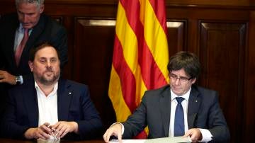 El presidente de la Generalitat, Carles Puigdemont, acompañado por el vicepresidente Oriol Junqueras, firma la convocatoria de referéndum en el Parlament