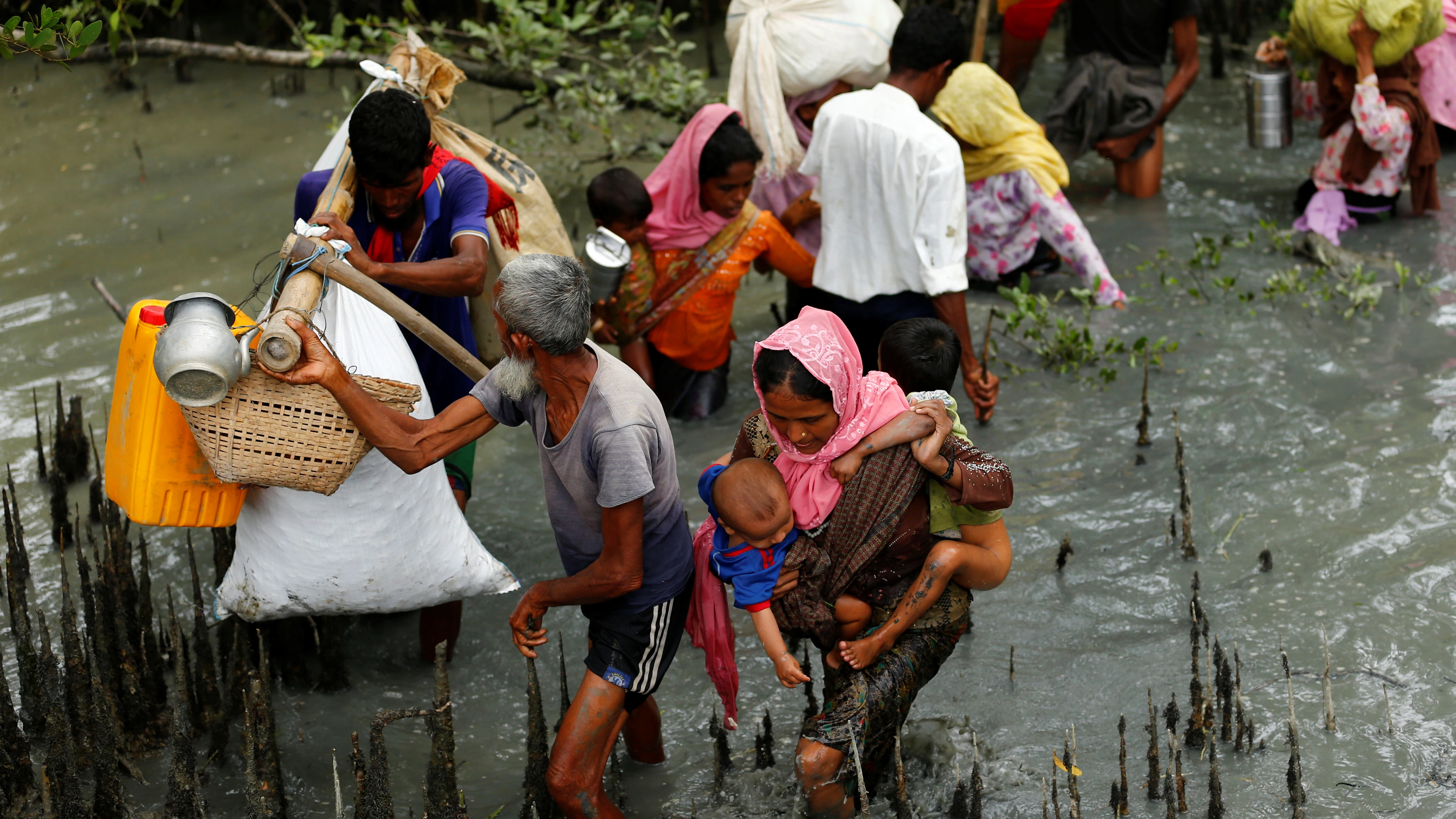 Refugiados rohingya caminan a través del agua después de cruzar la frontera en barco a través del río Naf en Teknaf, Bangladesh