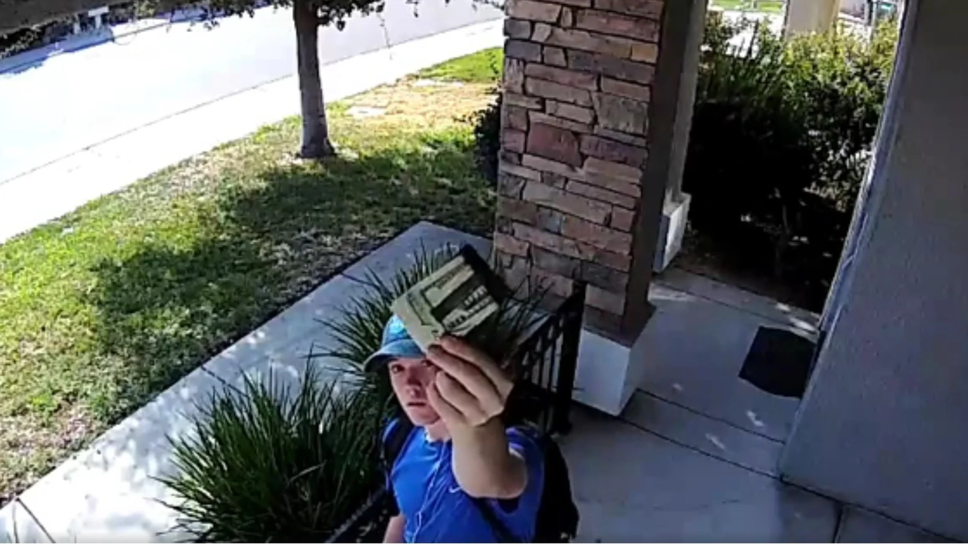 El joven muestra a la cámara de seguridad la cartera encontrada