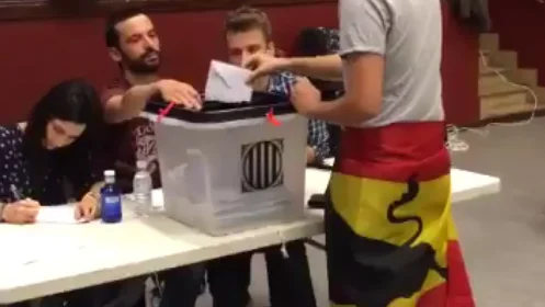 Un ciudadano acude a votar con una bandera de España