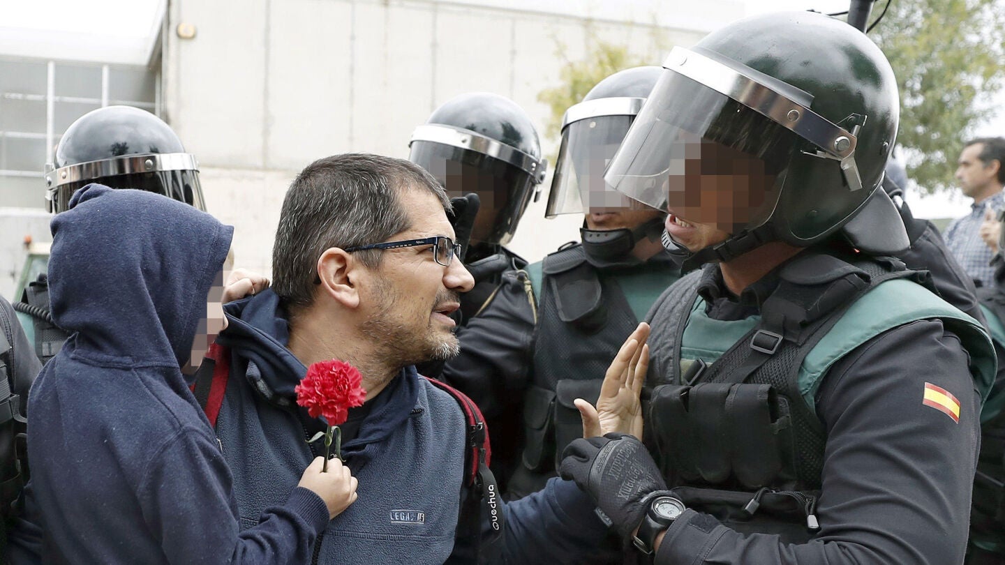 Un padre con su hijo en brazo conversa con un guardia civil ante uno de los colegios