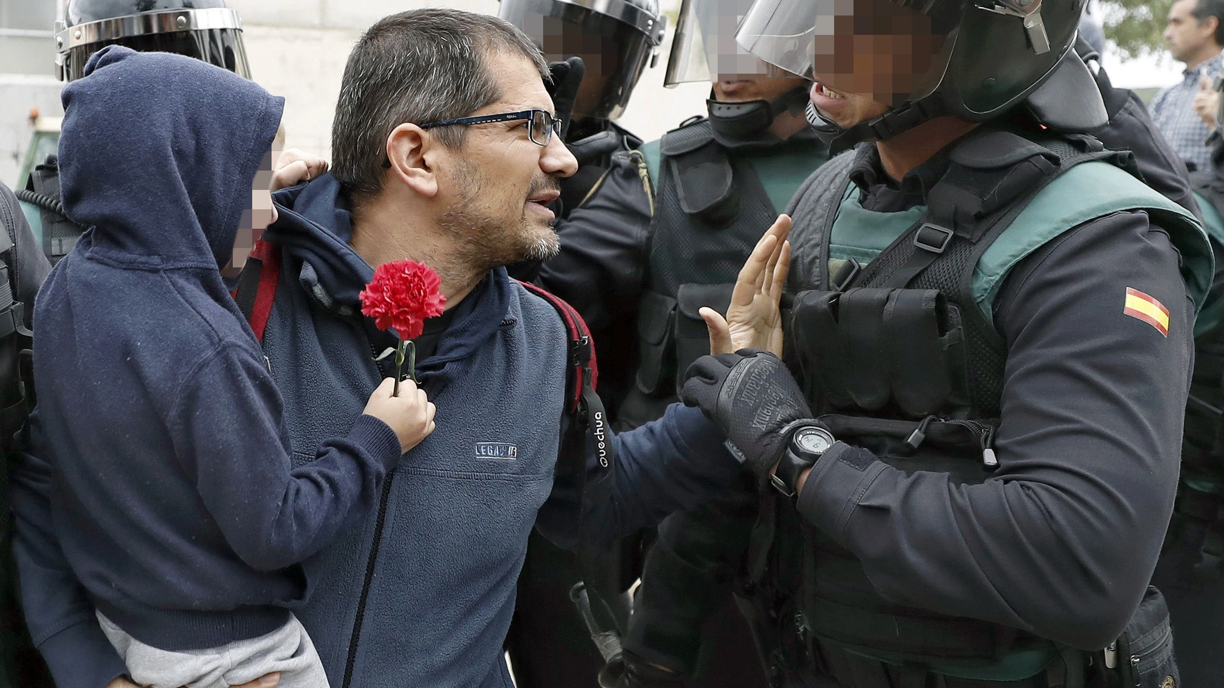 Un padre con su hijo en brazo conversa con un guardia civil ante uno de los colegios