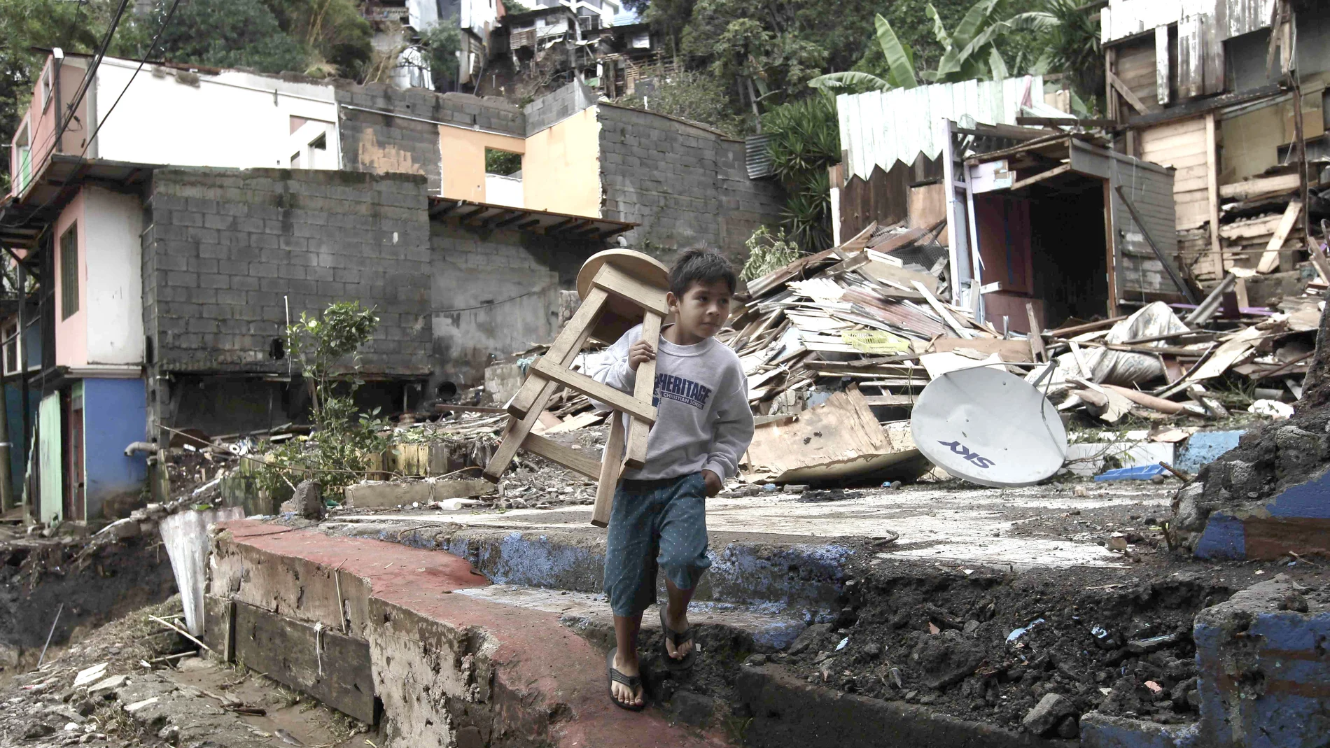 Un niño carga una silla en medio de los escombros en el cantón de Escazú