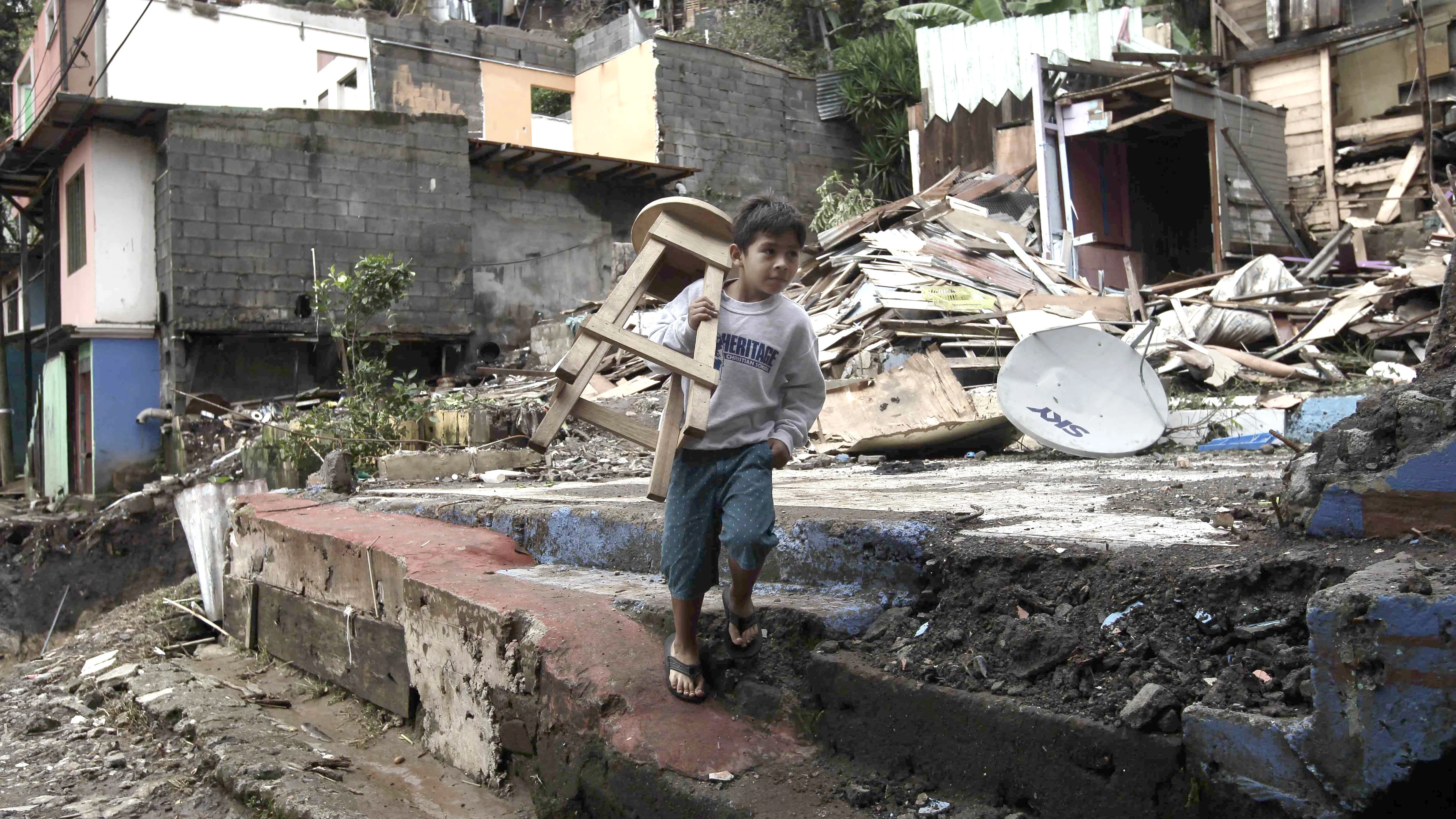 Un niño carga una silla en medio de los escombros en el cantón de Escazú