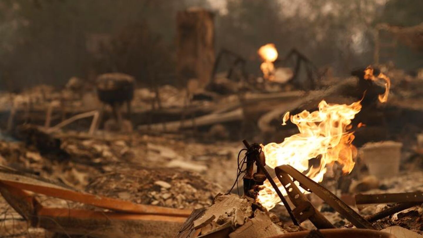 Vista del fuego saliendo de una pipa de gas de una casa quemada en California