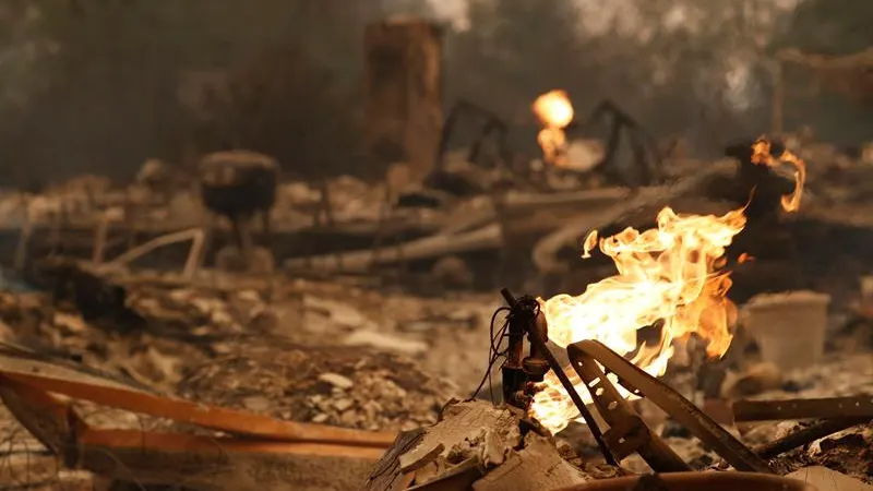 Vista del fuego saliendo de una pipa de gas de una casa quemada en California