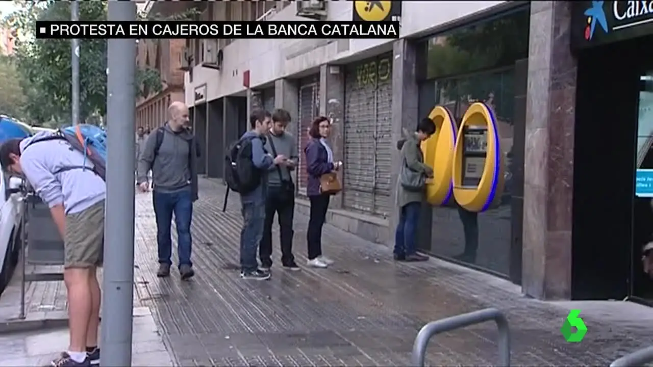 Algunos ciudadanos hacen cola en el cajero automático