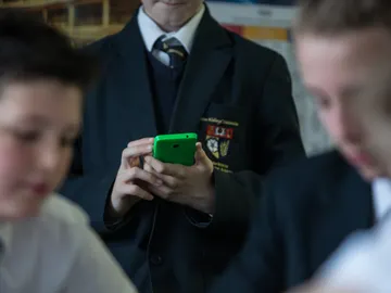 Un alumno con un móvil en el colegio Un alumno con un móvil en el colegio