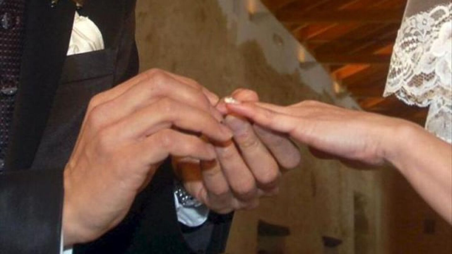 Manos de una pareja intercambiando los anillos en la ceremonia de su boda