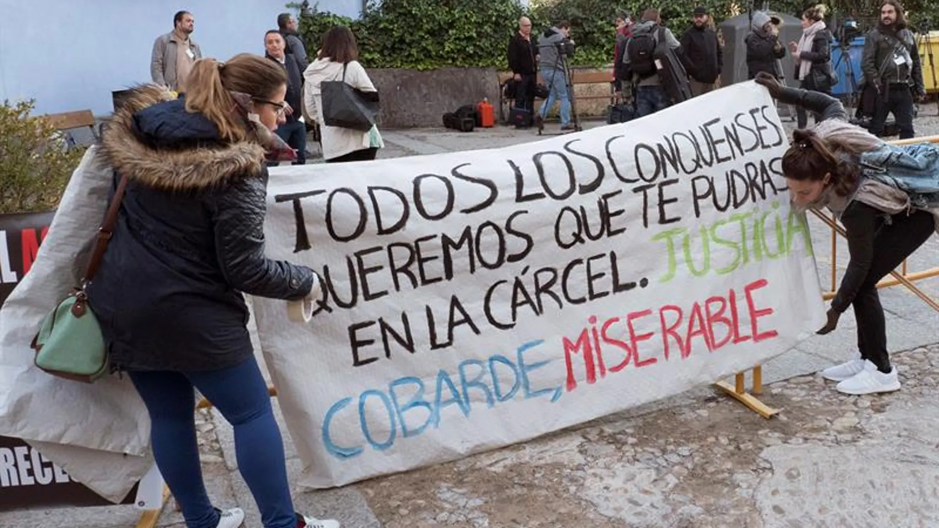 Amigos de las víctimas, Laura y Marina, colocanco una pancarta en la entrada de los juzgados a la llegada de Sergio Morate