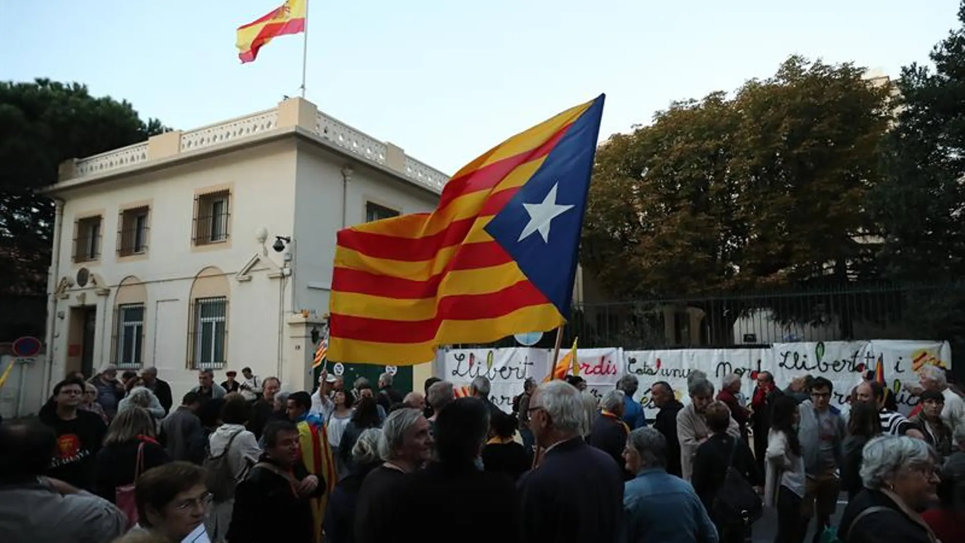 Personas sostienen banderas catalanas frente al consulado español en Perpiñán 