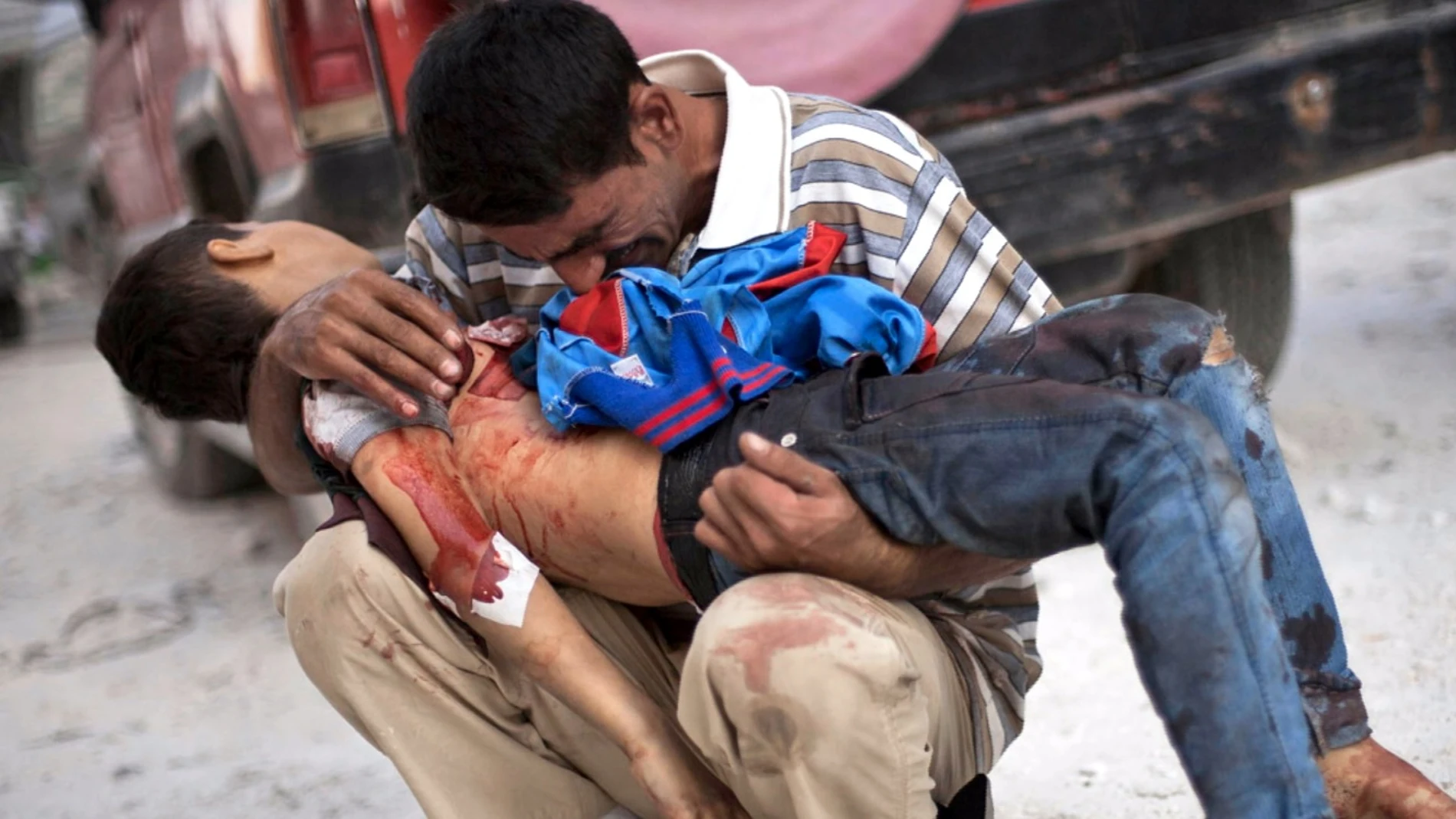 Un padre con su hijo muerto frente a un hospital de Alepo